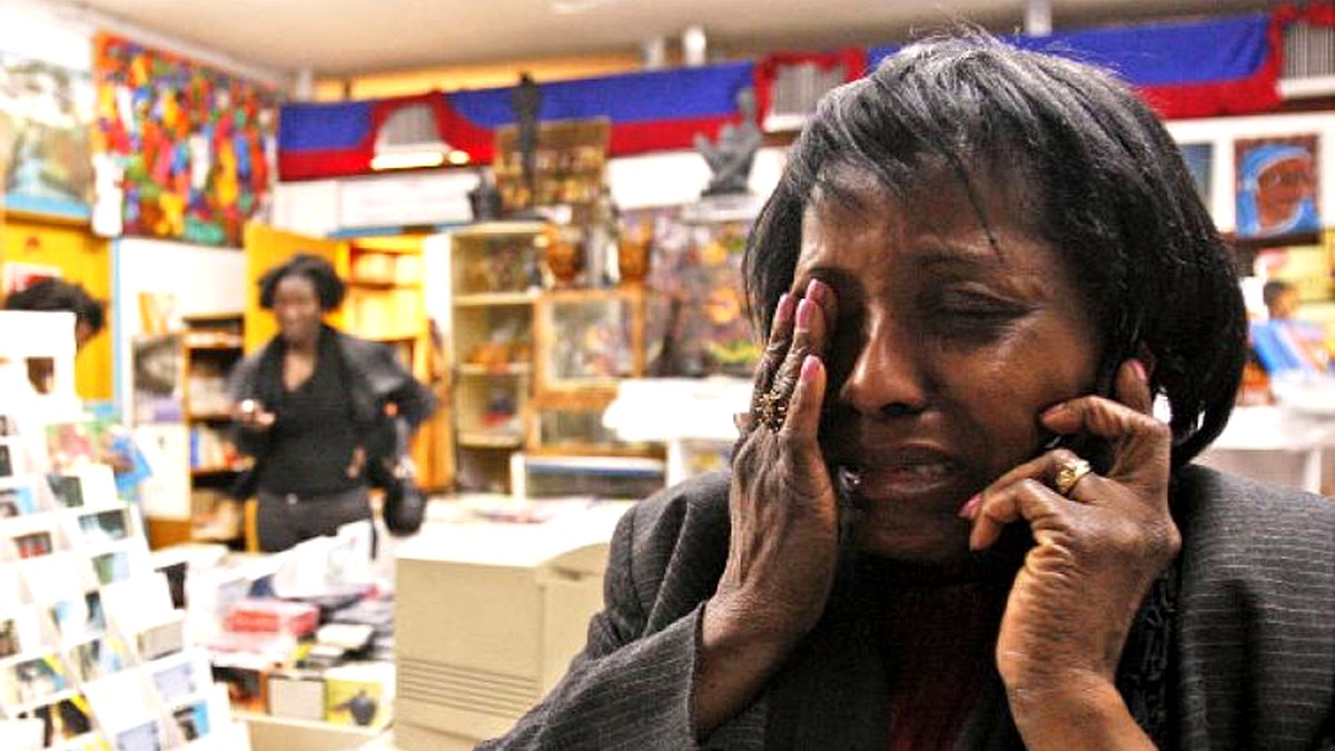 Femme en détresse au téléphone, illustrant le désespoir social et économique lié à la crise en Haïti.