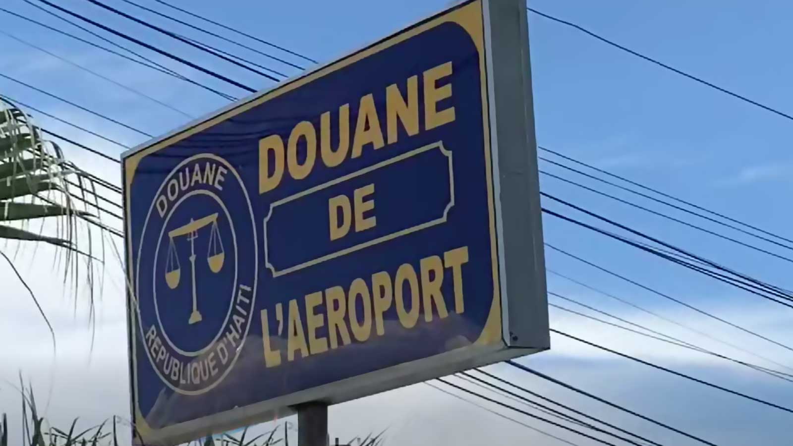 Panneau de la douane de l’aéroport Toussaint Louverture en Haïti, illustrant une protestation des agents douaniers.