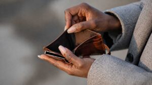 Mains d’une personne tenant un portefeuille vide, illustrant la perte de pouvoir d’achat et la vie chère en Haïti.