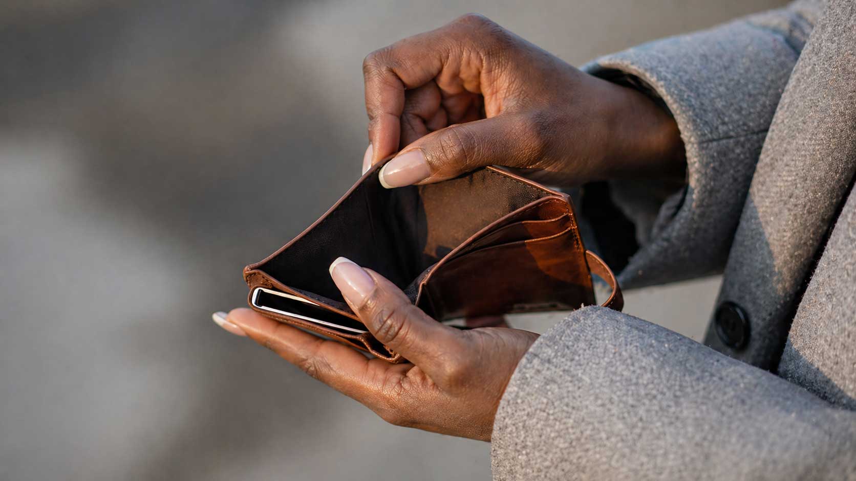 Mains d’une personne tenant un portefeuille vide, illustrant la perte de pouvoir d’achat et la vie chère en Haïti.