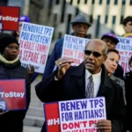 Manifestants tenant des pancartes demandant le renouvellement du TPS pour les Haïtiens aux États-Unis.