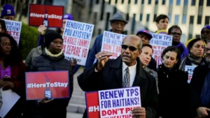 Manifestants tenant des pancartes demandant le renouvellement du TPS pour les Haïtiens aux États-Unis.