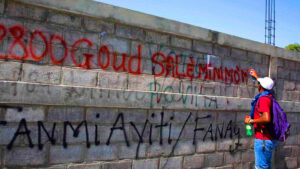 Mur couvert de graffitis sociaux en Haïti, illustrant les revendications liées au coût de la vie et aux salaires.