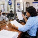 Une employée et un usager dans un bureau administratif traitent des documents officiels à un comptoir de service.