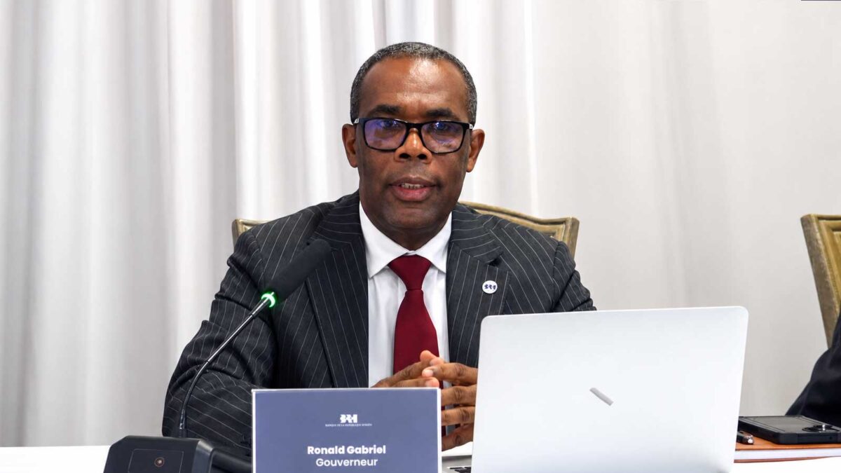 Responsable de la BRH prenant la parole devant un microphone et un ordinateur lors d’une présentation sur la situation économique d’Haïti.