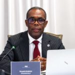 Responsable de la BRH prenant la parole devant un microphone et un ordinateur lors d’une présentation sur la situation économique d’Haïti.