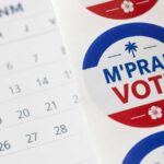 Autocollants « M’pral Vote » aux couleurs d’Haïti posés sur un calendrier avec une date d’élection entourée.