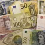 Billets en dollars, euros, yens, livres sterling, dollars canadien et australien, renminbis et francs suisses autour d’une flèche illustrant l’évolution des réserves de change.