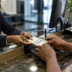 Une cliente et une employée effectuent un transfert d’argent en dollars à un comptoir.