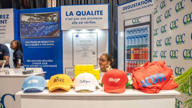 Stand de la Caribbean Bottling Company lors de la Semaine de l’Industrie 2026 en Haïti, présentant des produits et informations sur la qualité et la production.